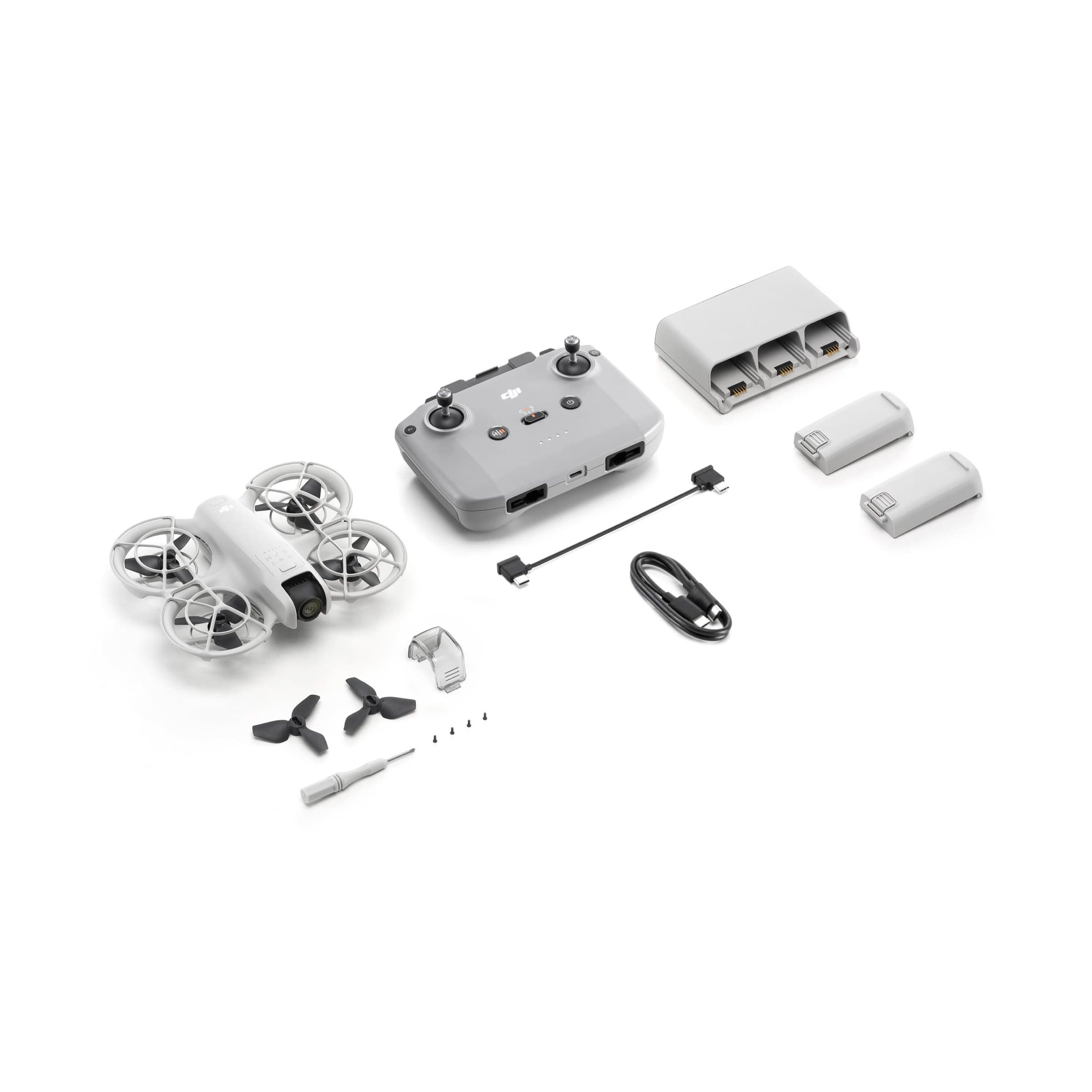 The DJI Neo Fly More Combo laid out: the drone, the RC-N3 remote controller, three batteries, the Two-Way Charging Hub, cables, spare propellers, a screwdriver and screws